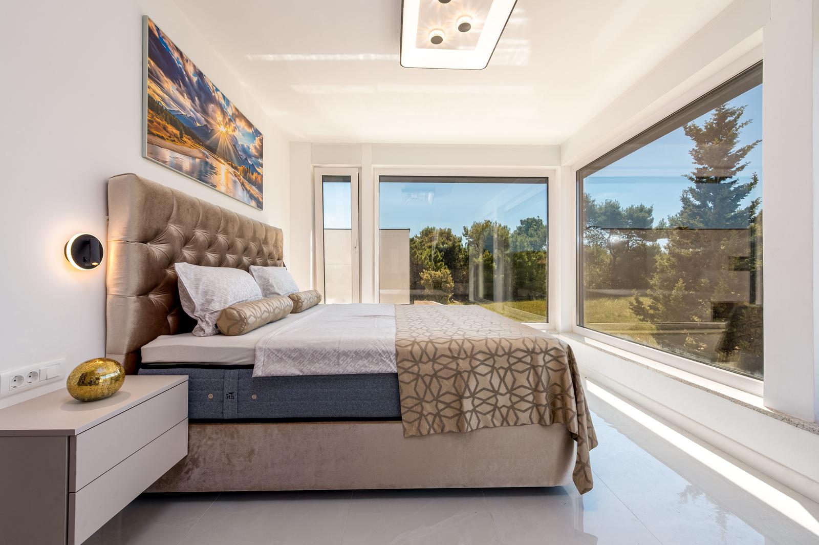 Schlafzimmer mit großem Bett, Fenstern und Wandbild.