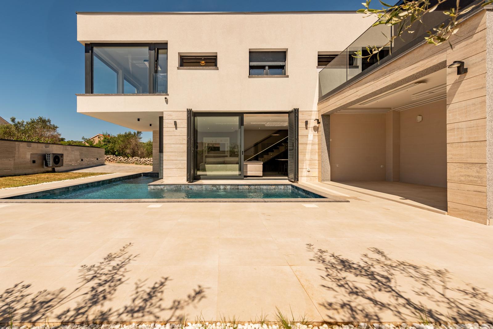 Moderne Villa mit Pool und Terrasse. Glasfront öffnet sich zum Innenraum.