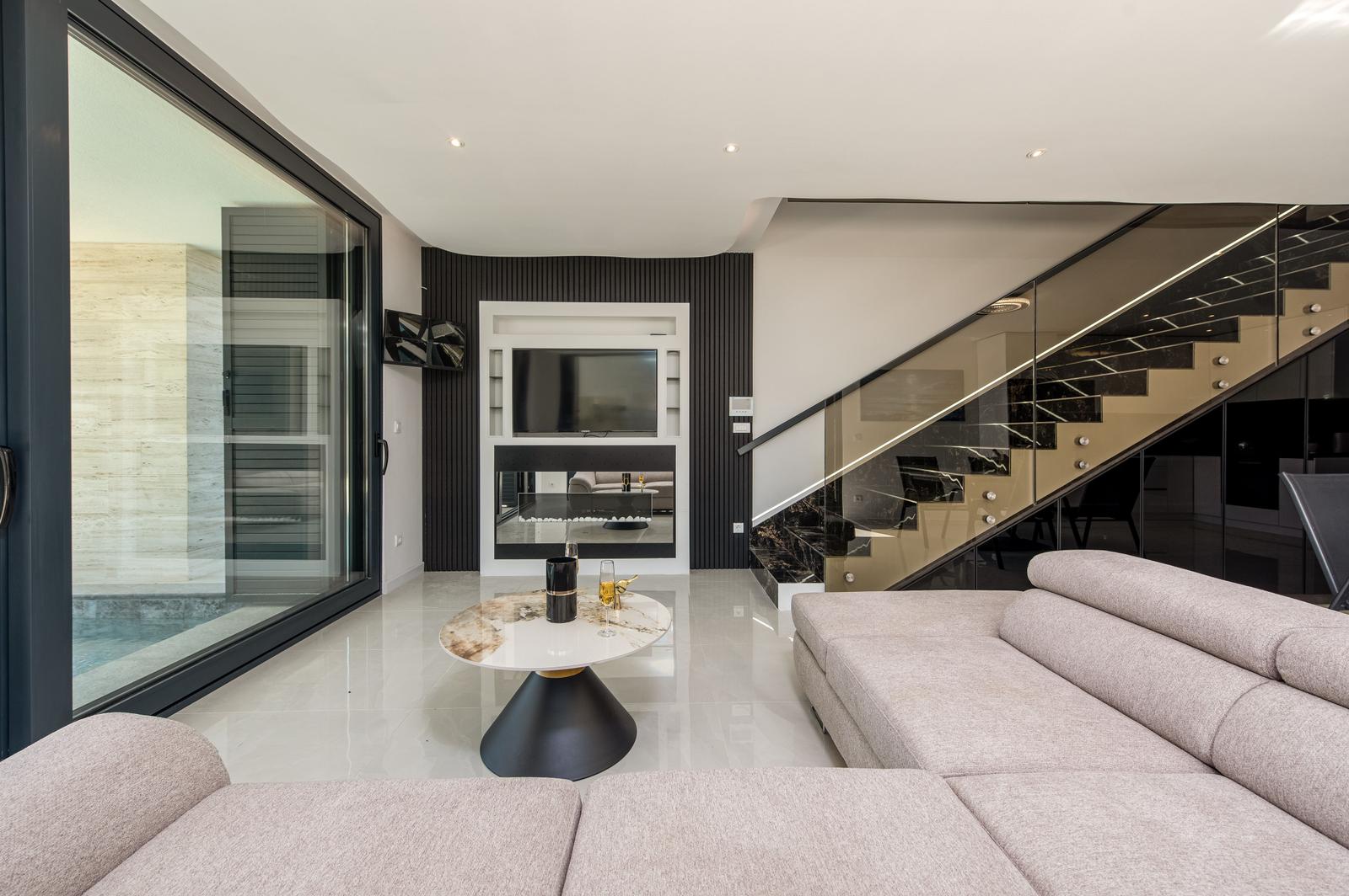 Moderne Wohnfläche mit Sofa, Tisch und Glasgeländer-Treppe.