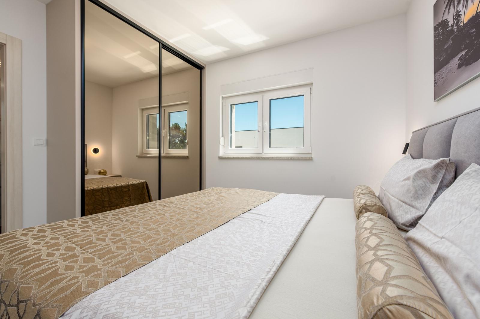 Schlafzimmer mit Doppelbett, Spiegeltüren und Fenster mit Blick.