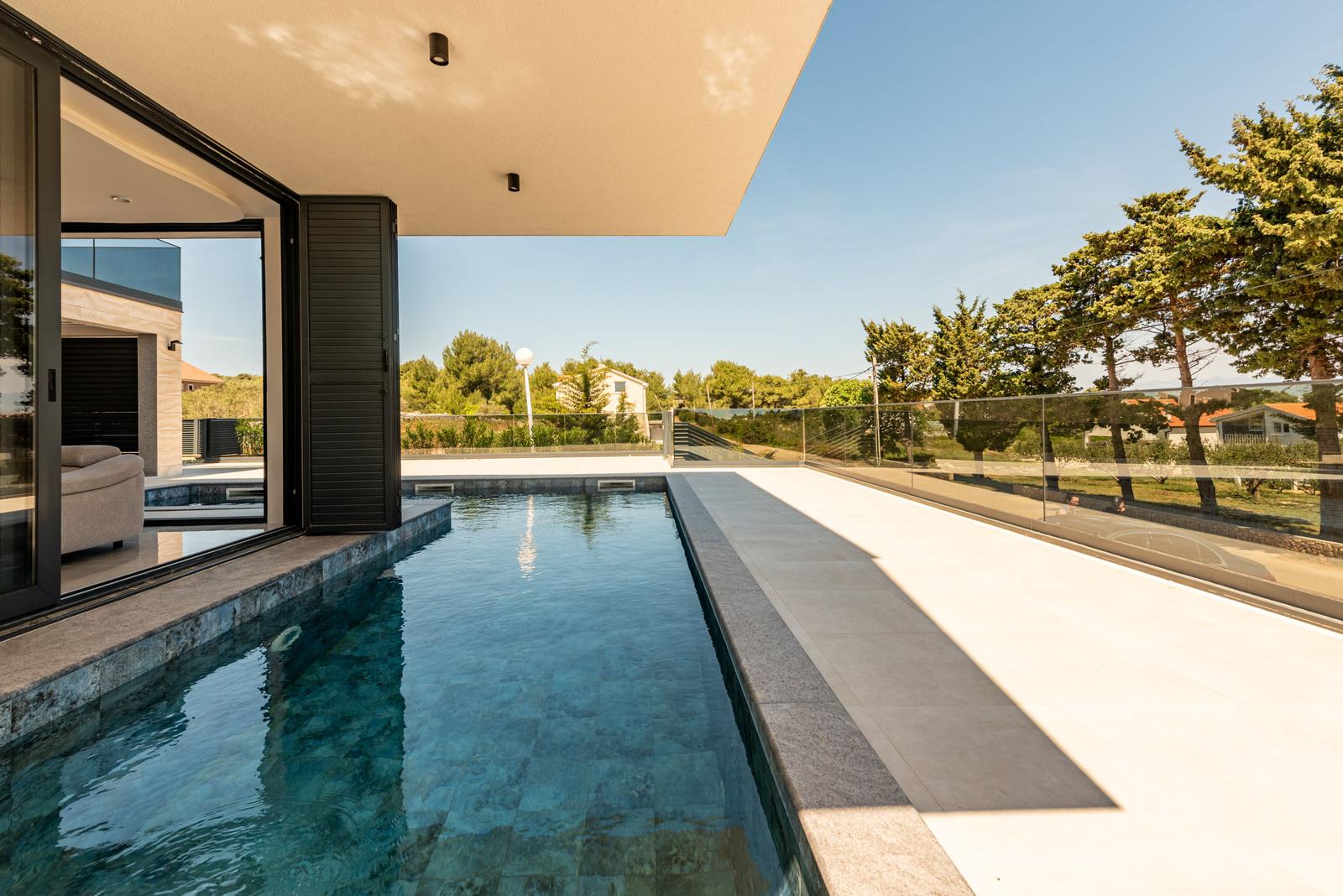 Pool mit Glasgeländer und Blick auf Bäume und Himmel