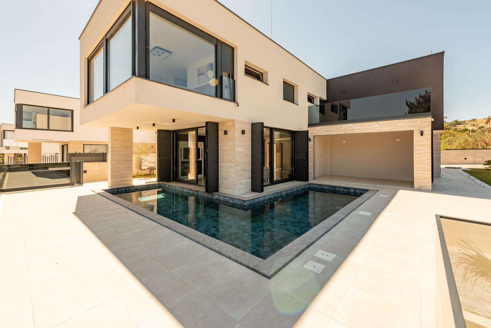 Moderne Villa mit Pool und Terrasse. Glasfassade und Steinmauer.