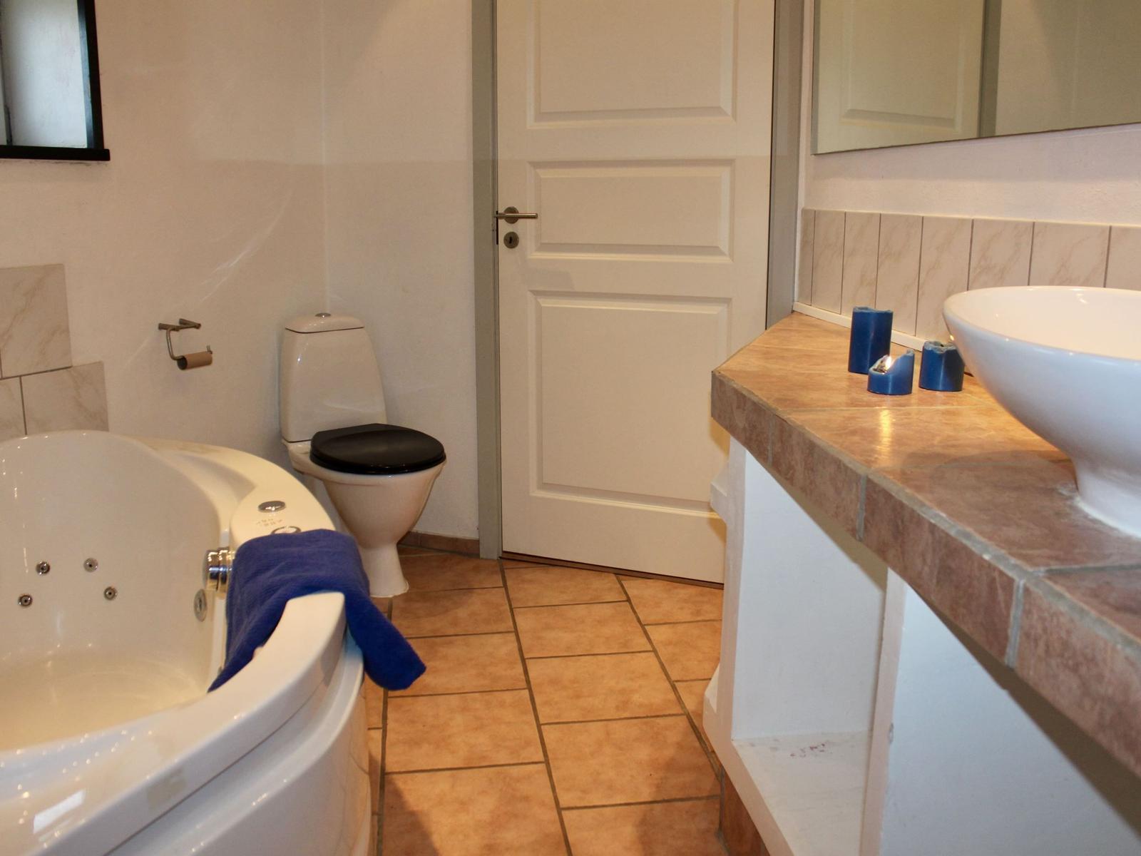 Bad mit Whirlpool, Toilette und Waschtisch mit blauen Kerzen.