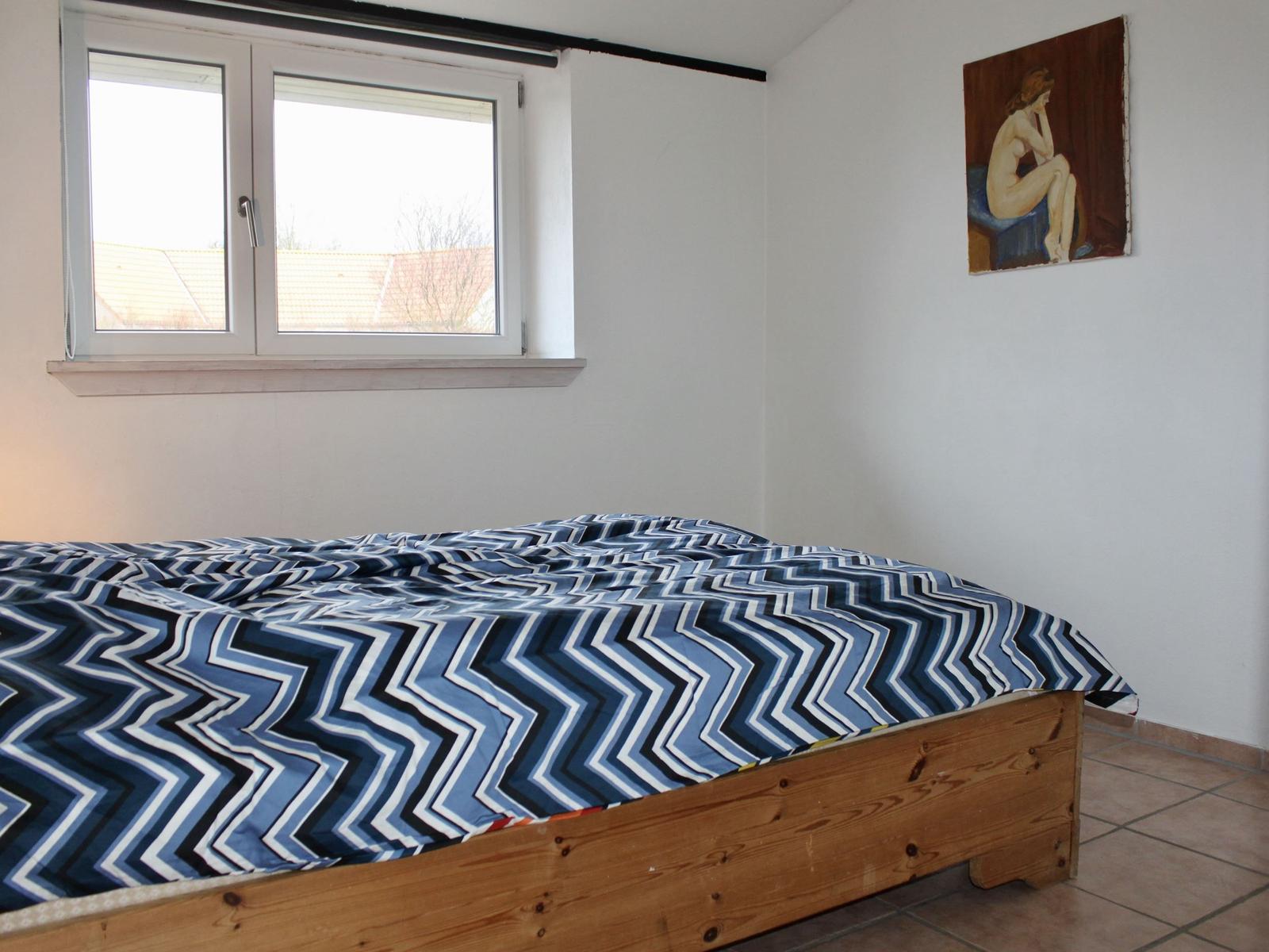 Schlafzimmer mit Bett, Fenster und Wandbild.