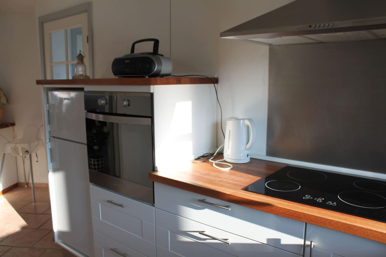 Küche mit Herd, Backofen, Kühlschrank und Wasserkocher.