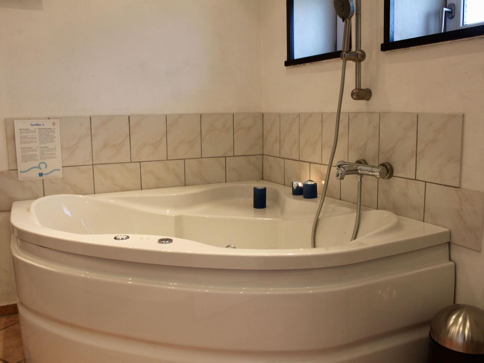 Eckbadewanne mit Duschkopf und Kerzen