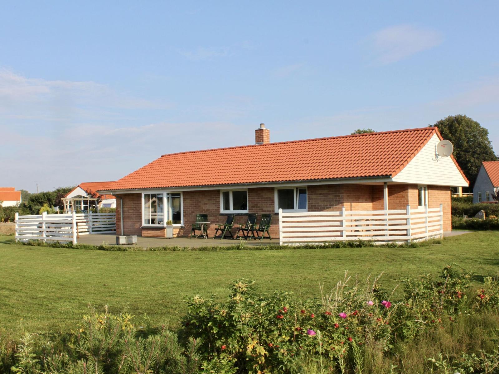 Ein Haus mit rotem Dach und weißem Zaun im Garten.