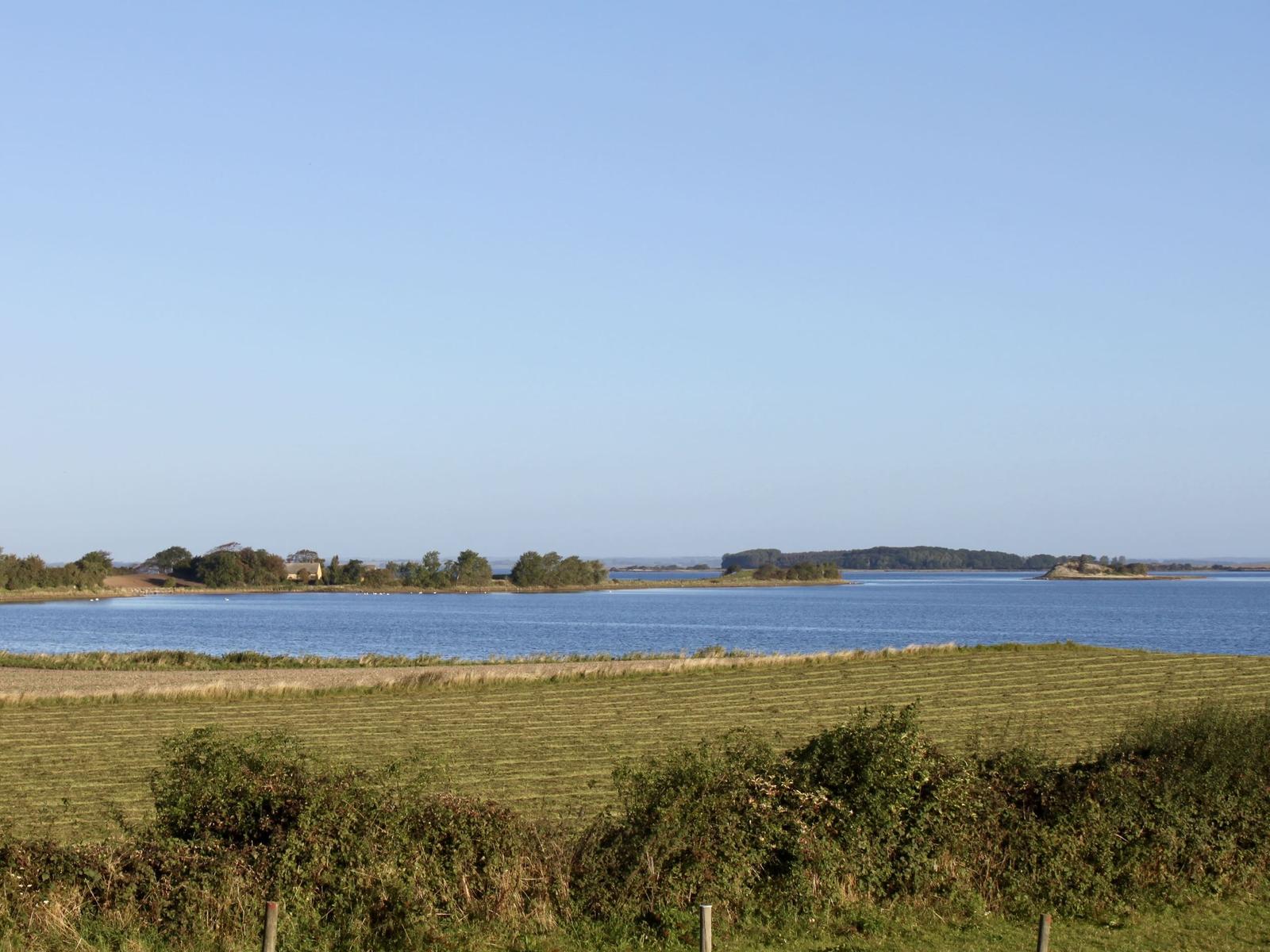 Weitläufiger Blick auf Wasser und Inseln mit grünen Feldern im Vordergrund.