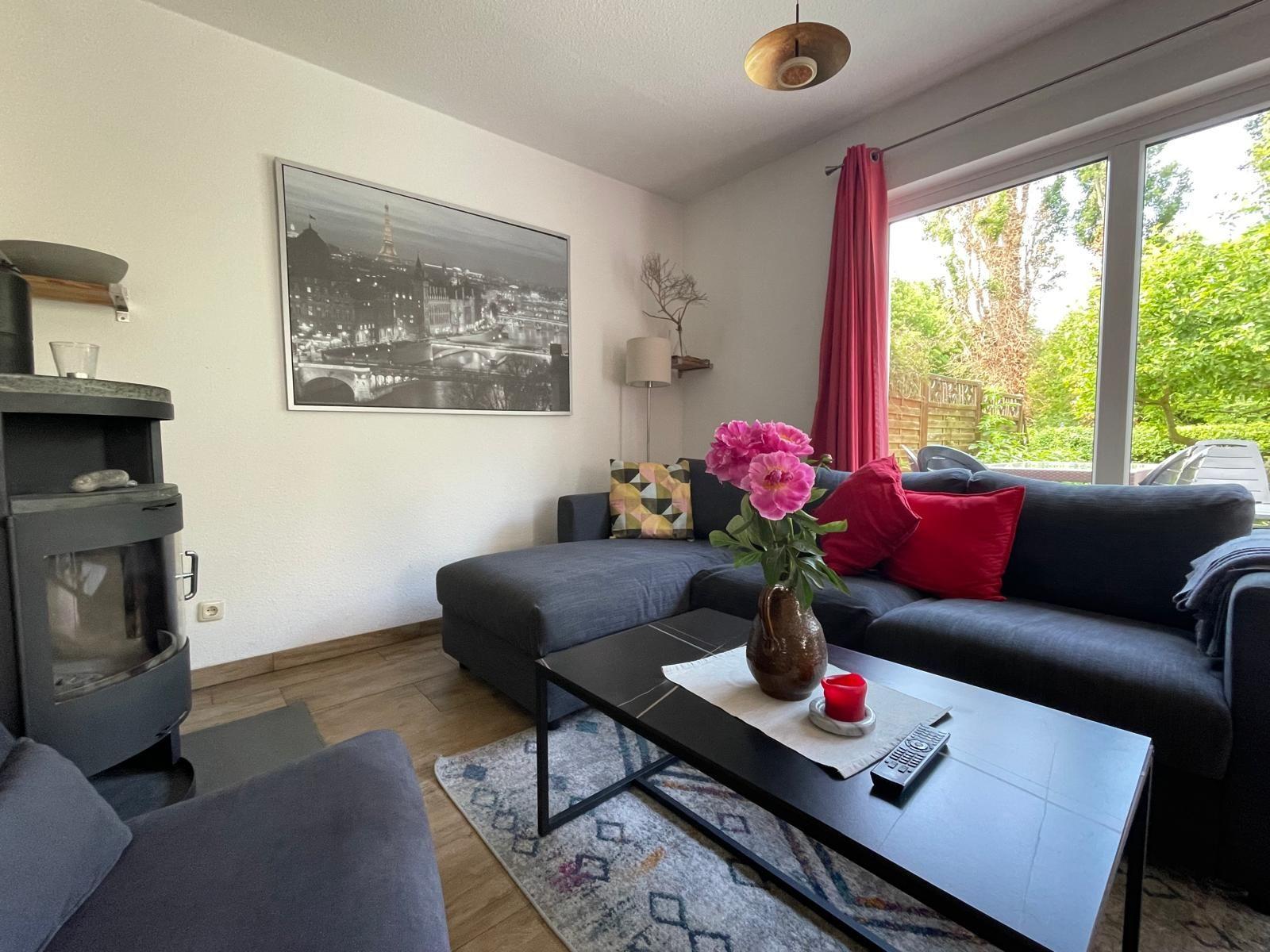 Wohnzimmer mit Sofa, Kamin und Blick auf grünen Garten.