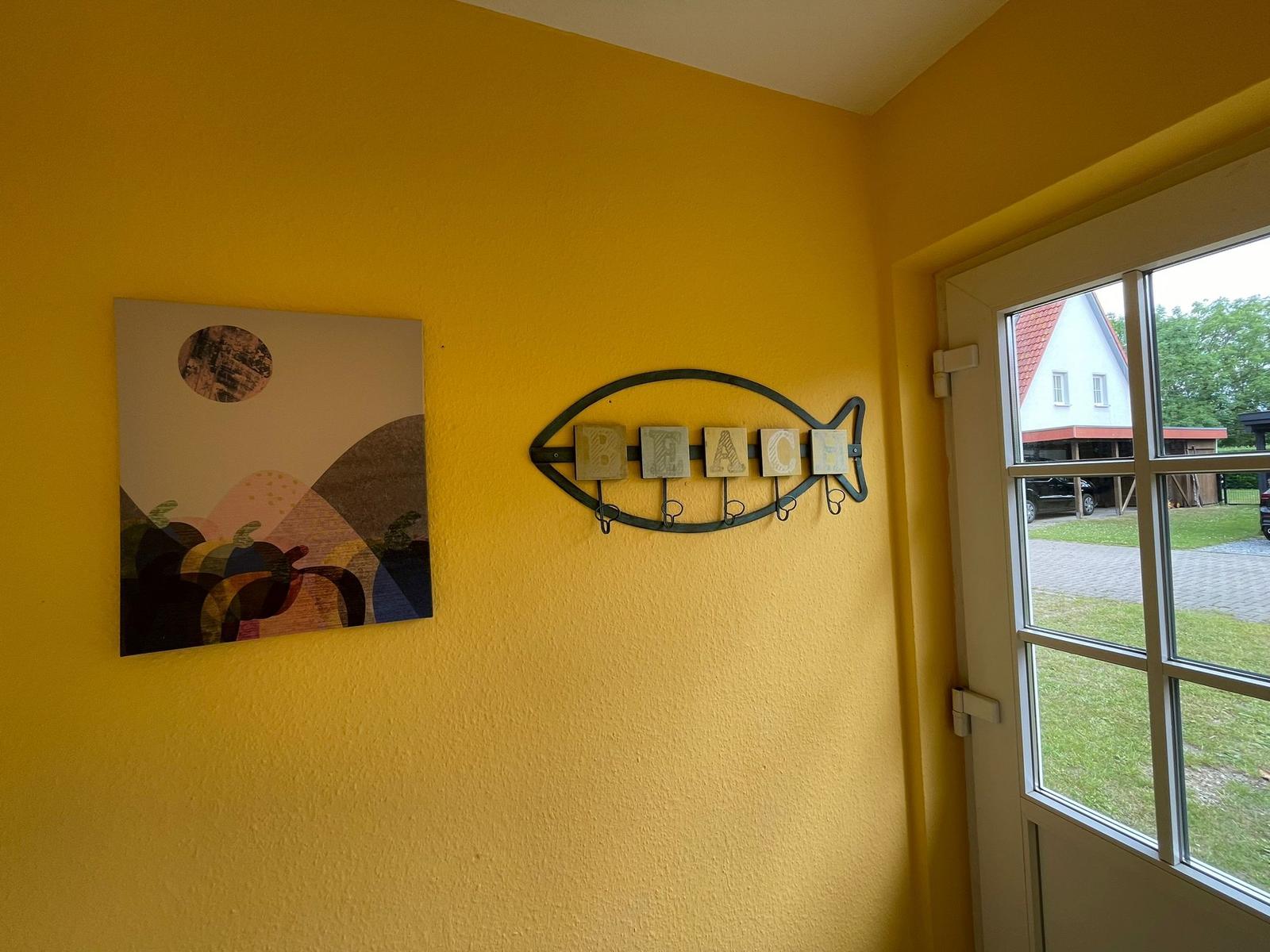 Gelber Raum mit Wandbild und Fischdekoration mit Buchstaben.