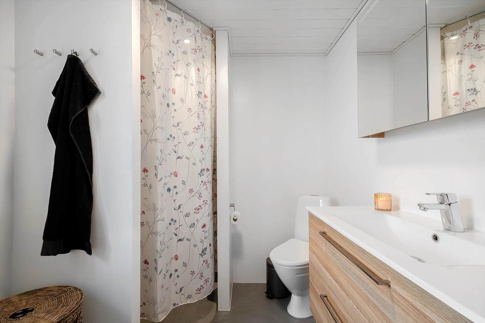 Badezimmer mit Dusche, Toilette und Waschbecken mit Spiegel.