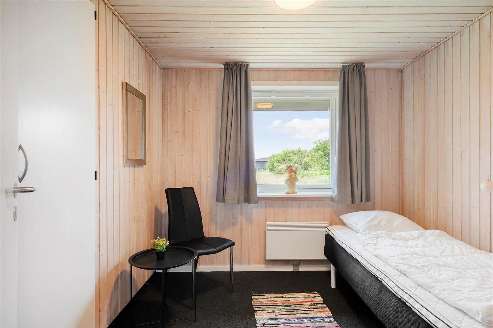 Ein Schlafzimmer mit Bett, Stuhl und Fenster mit Blick auf die Landschaft.
