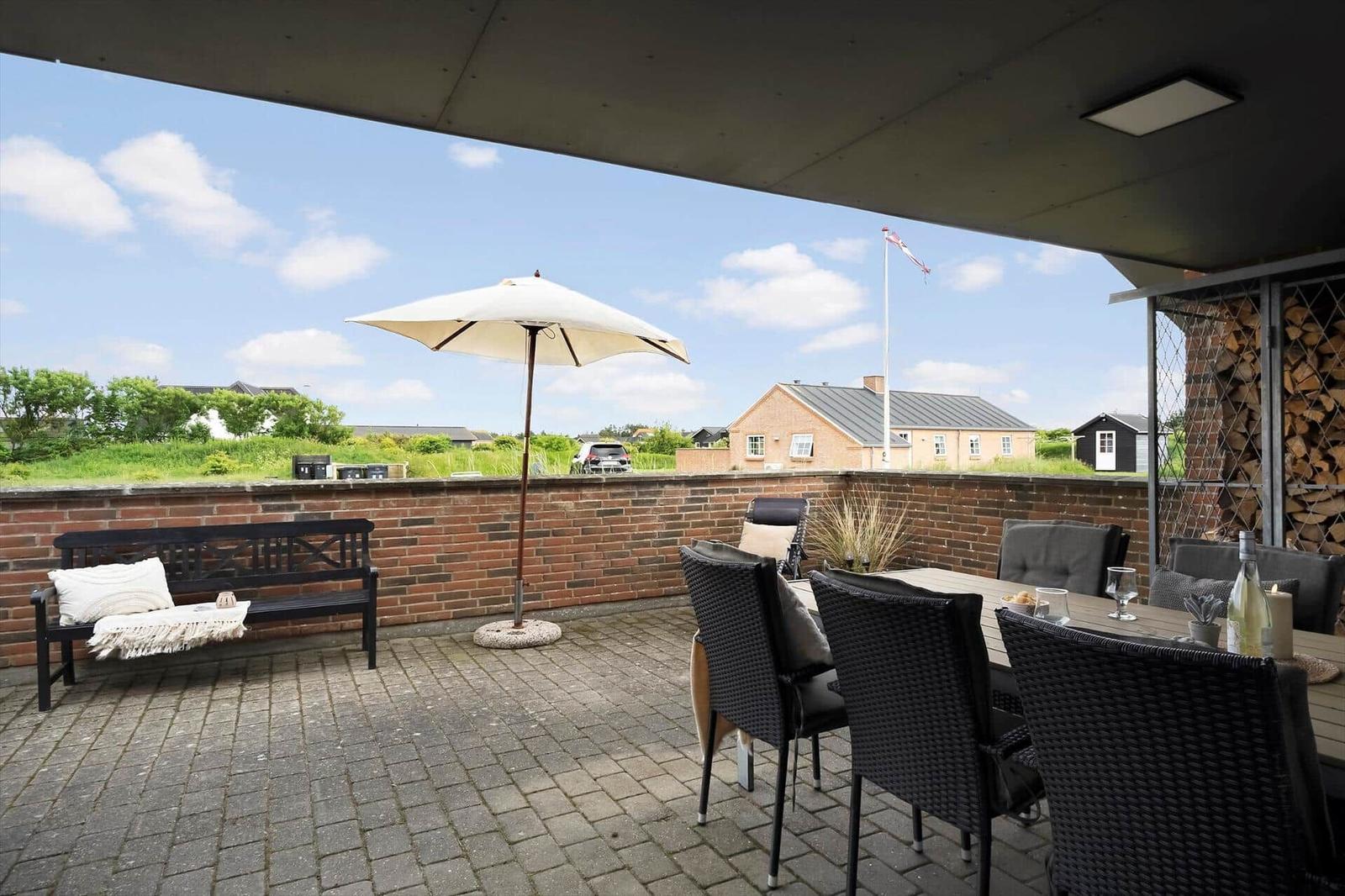 Terrasse mit Sitzgruppe, Sonnenschirm und Blick auf Umgebung.
