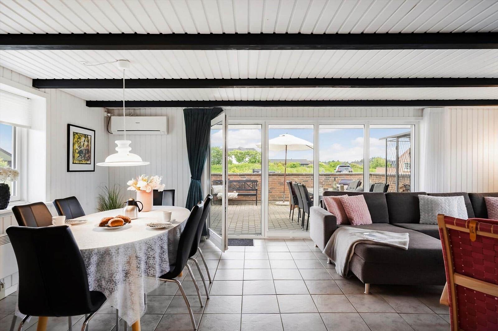 Esszimmer mit Tisch und Stühlen, Wohnbereich mit Sofa und Blick auf Terrasse.