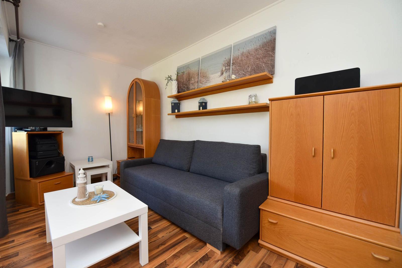 Wohnzimmer mit Sofa, TV, Schränken und Holzboden.