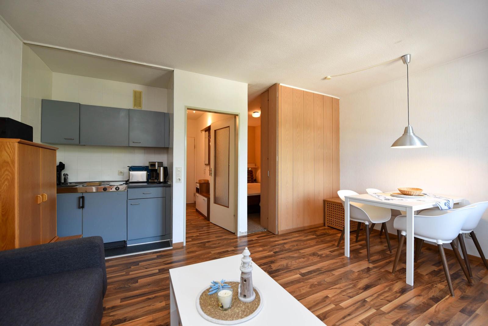 Wohnung mit Küche, Essbereich und Schlafzimmer. Holzboden und moderne Möbel.