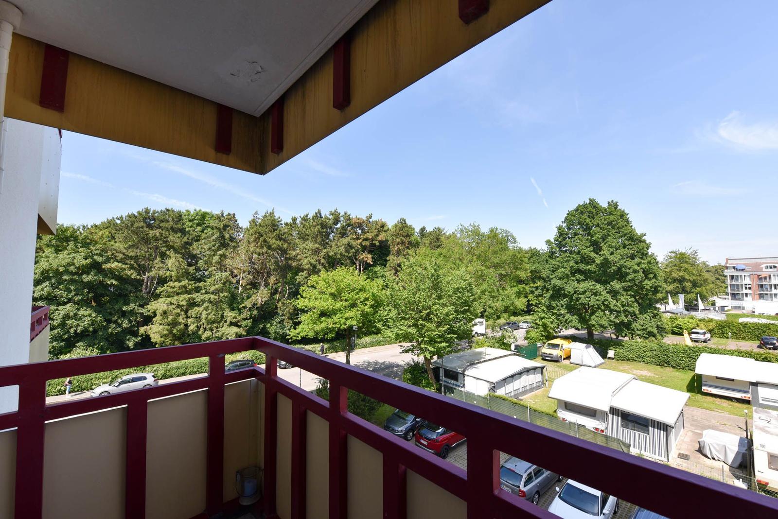 Balkon mit Blick auf Bäume und Wohnmobile.