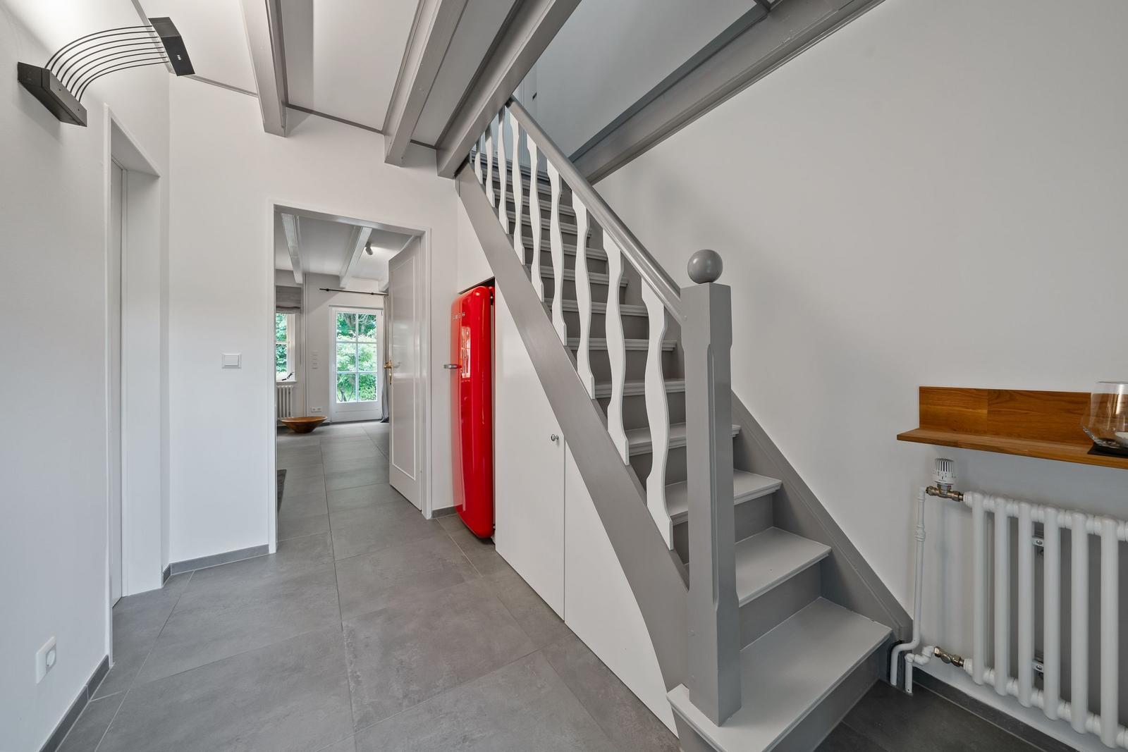 Haus mit Treppe, rotem Kühlschrank und Fensterblick ins Grüne.