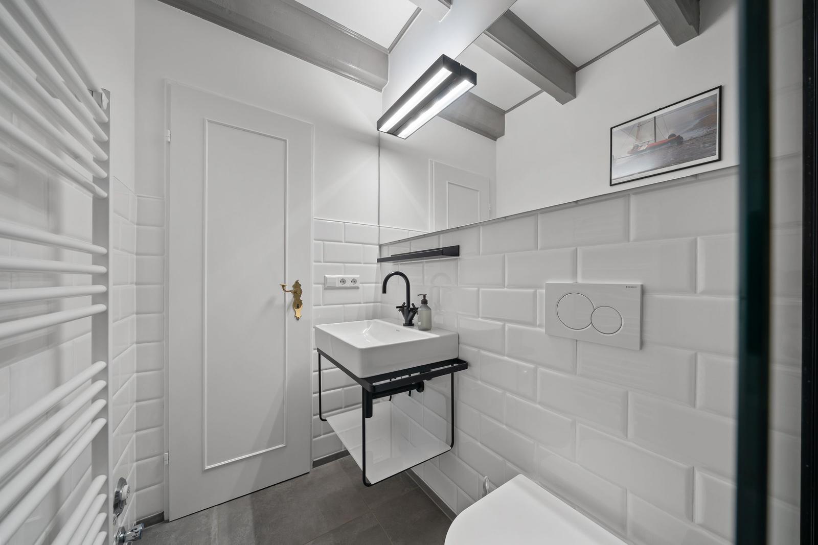 Badezimmer mit Waschbecken, Toilette und Heizung.
