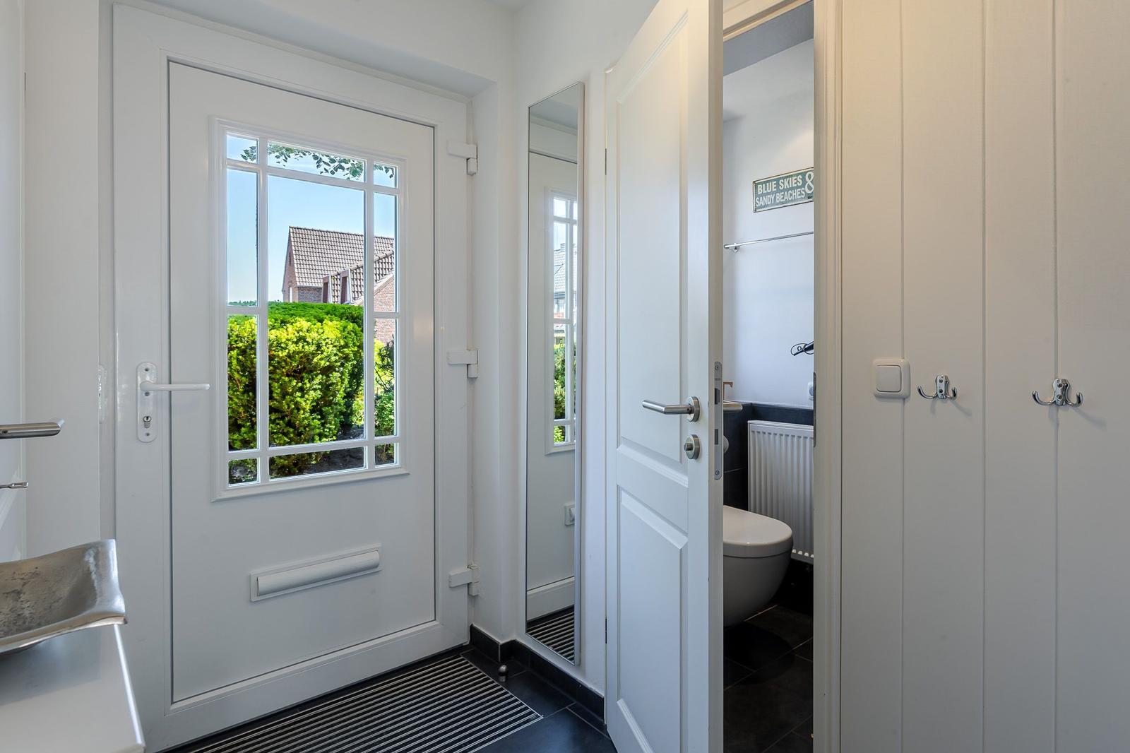 Helle Eingangshalle mit Blick auf grünen Garten und Badezimmer mit Toilette.