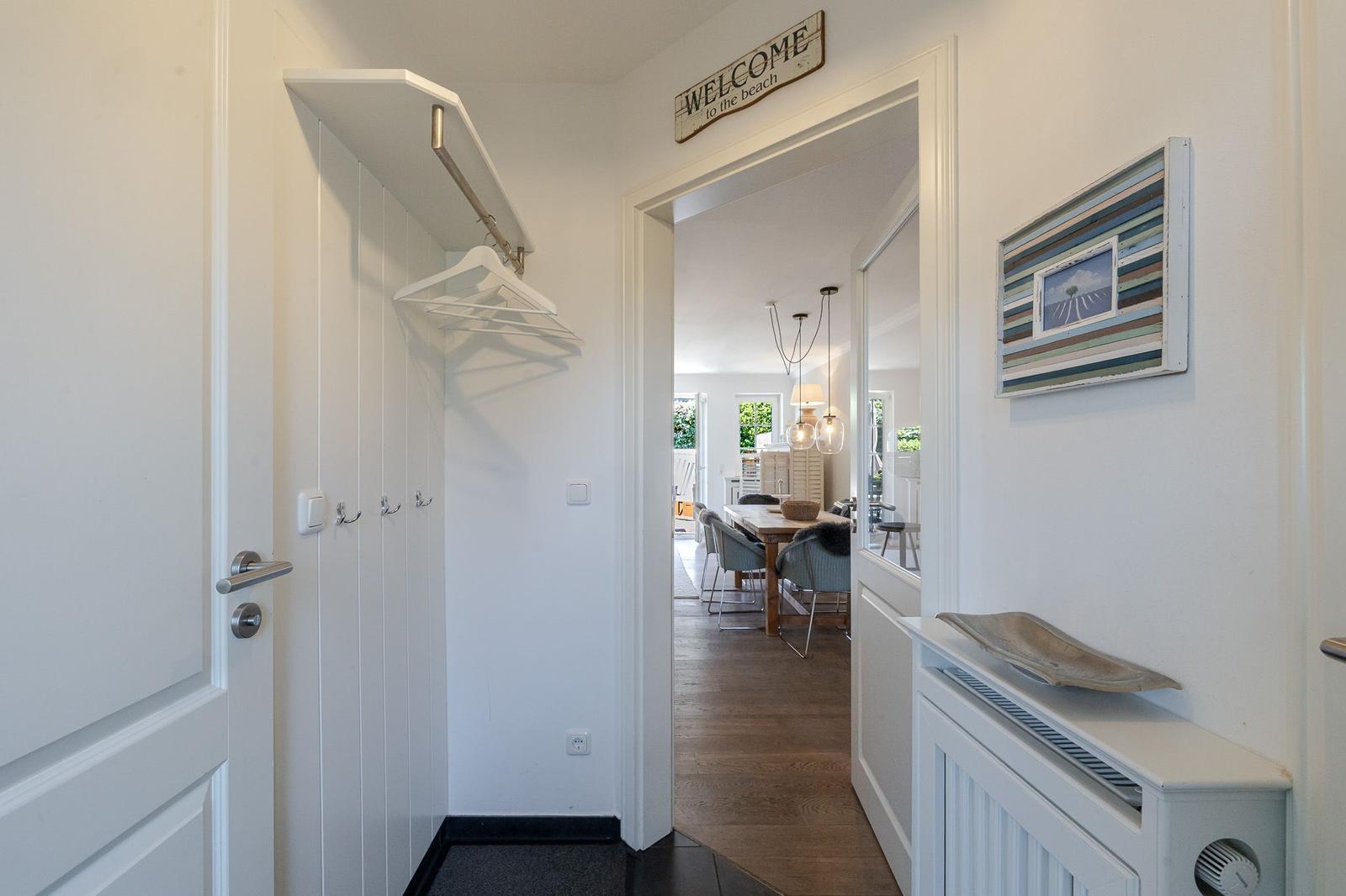 Hallenflur mit Garderobe und Blick in Esszimmer. Wandbild und Willkommensschild.