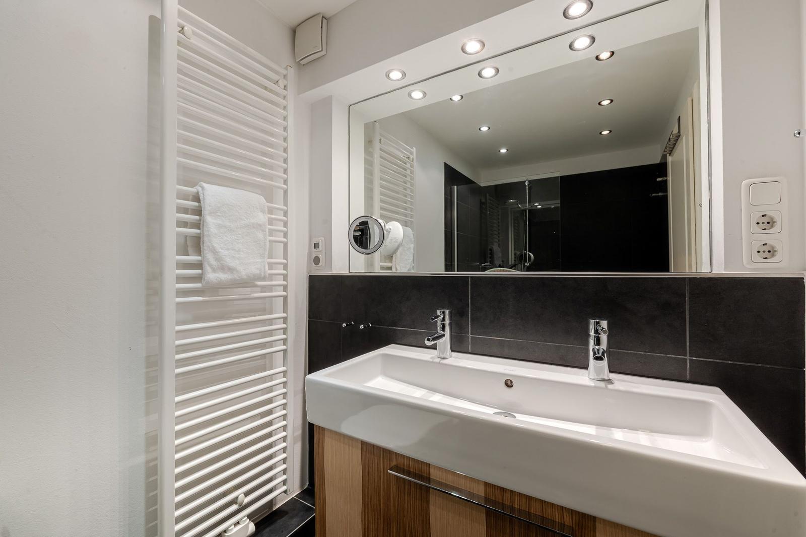 Badezimmer mit Waschbecken, Spiegel und Handtuchheizung.