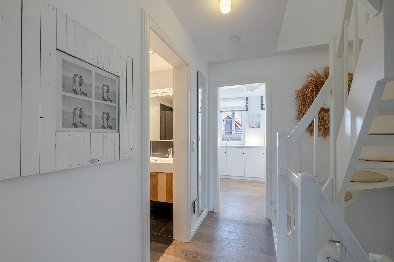 Flur mit Treppe, Bad und Küchenbereich. Wandbild mit Strandmotiven.