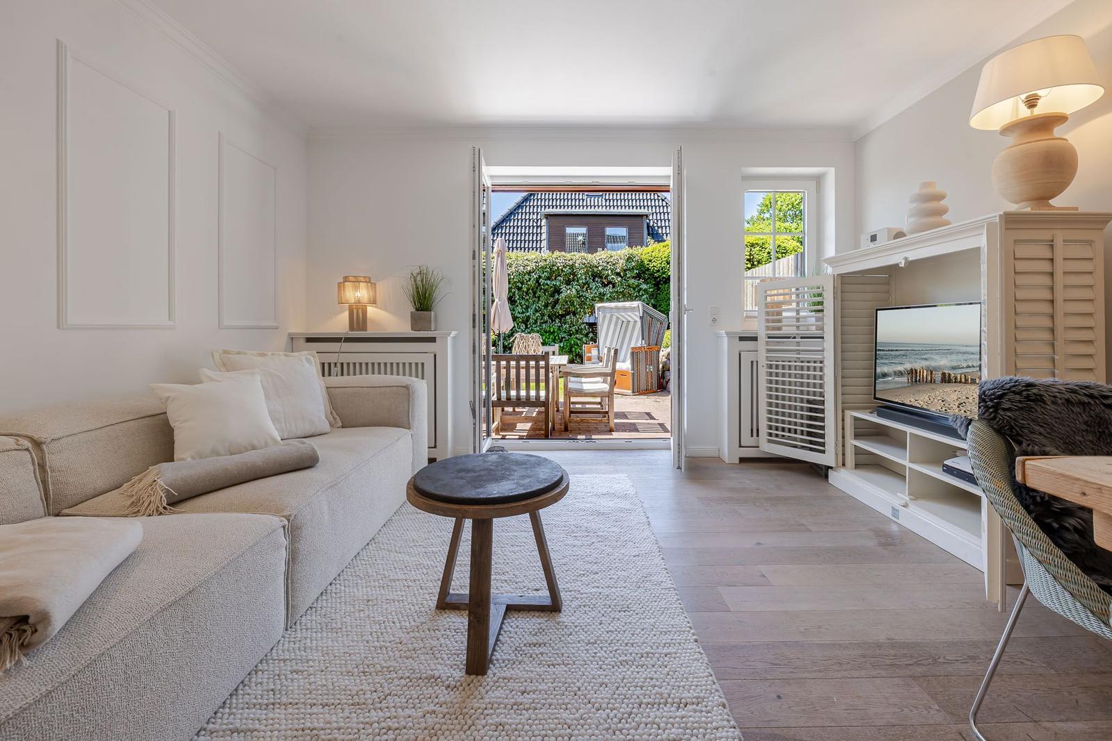 Wohnzimmer mit Sofa, Fernseher und Blick auf die Terrasse.