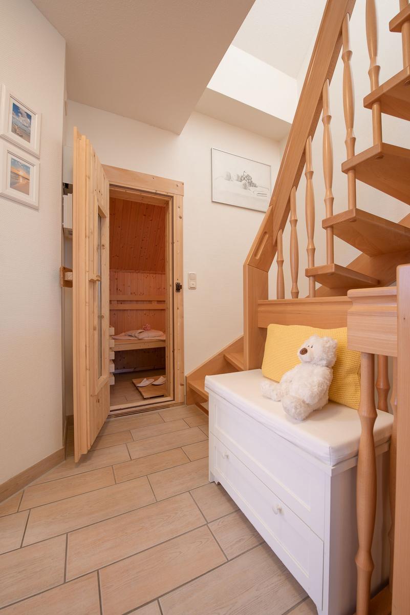 Hölzerner Treppenaufgang neben einer Sauna mit Sitzbank und Plüschbären.