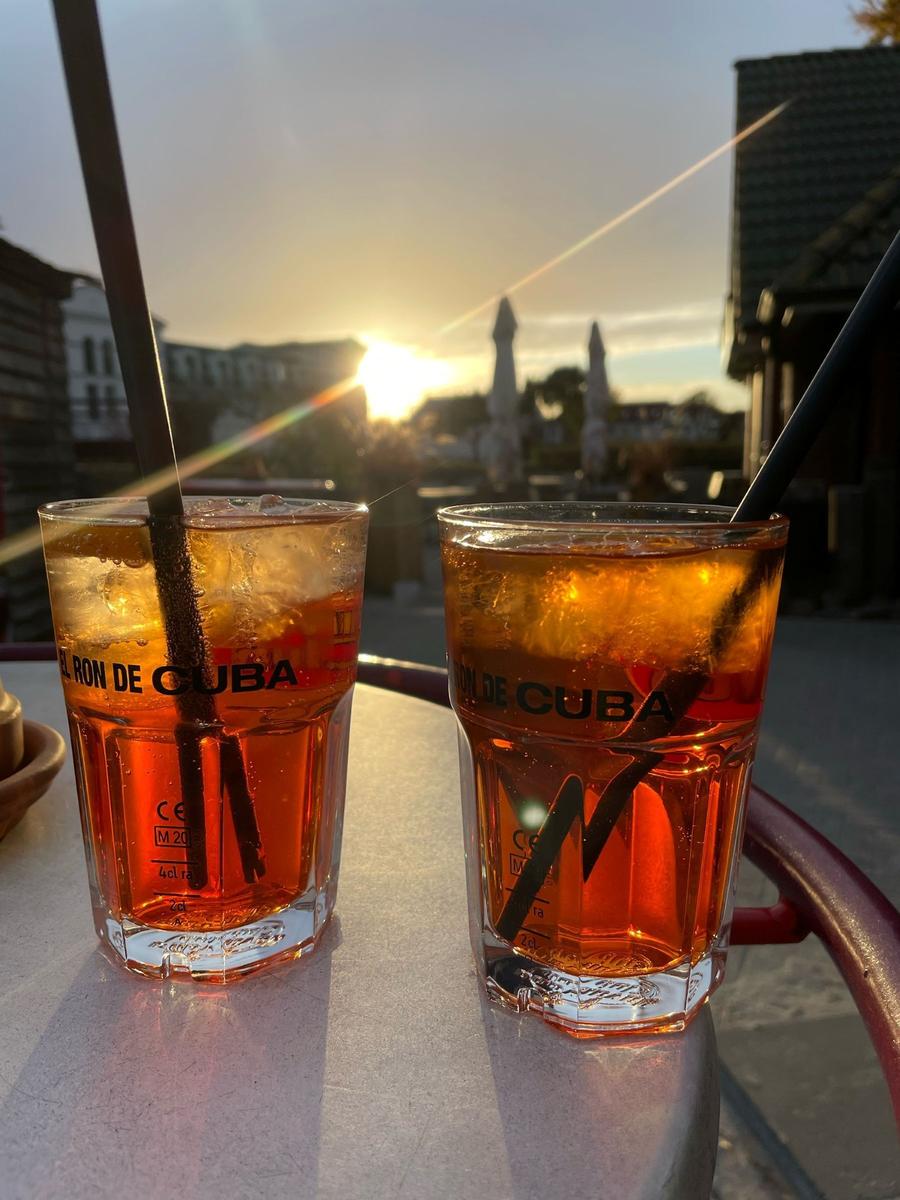 Zwei Gläser mit Getränk stehen auf einem Tisch vor Sonnenuntergang.