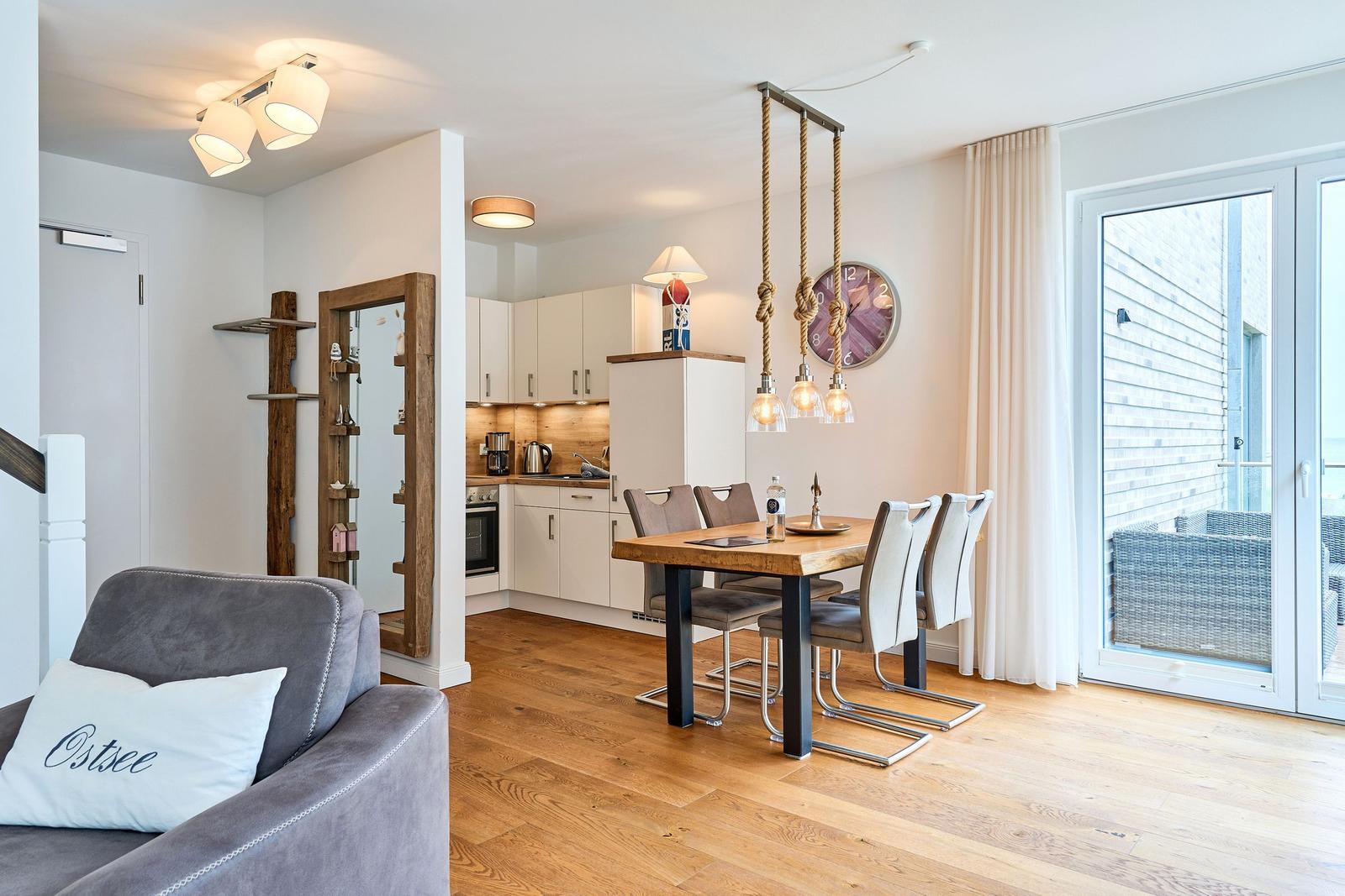Wohn- und Essbereich mit Holzboden, Esstisch, Küchenzeile und Terrasse.