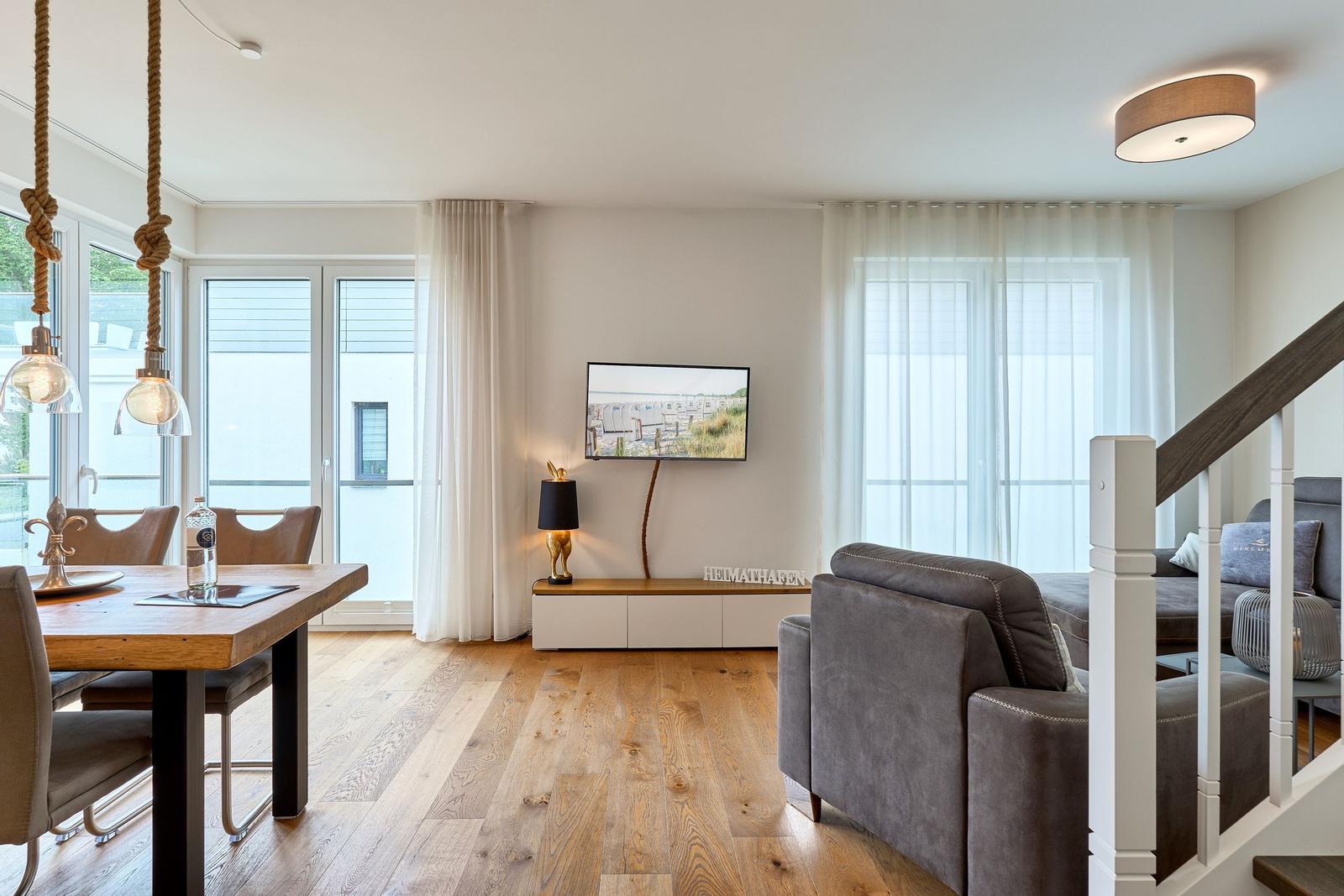 Wohn- und Essbereich mit Holzboden, TV und Essplatz.