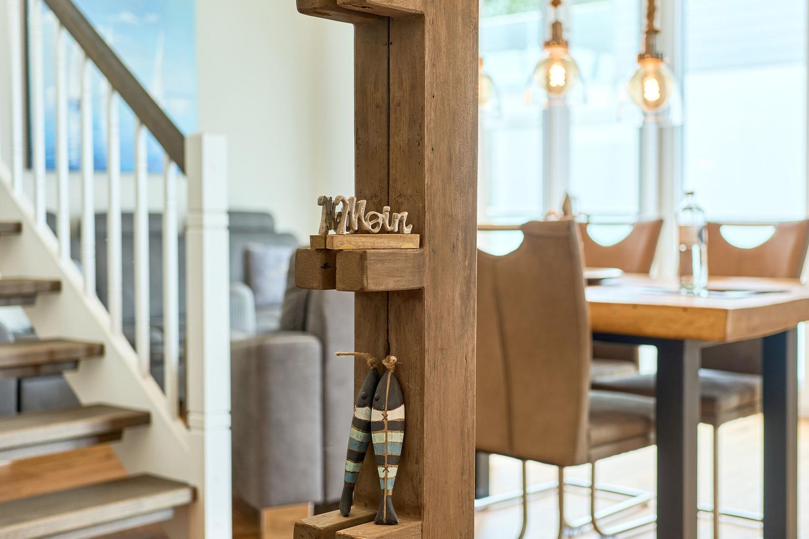 Holzstufe mit Dekoration, Treppenhaus und Essbereich im Hintergrund.