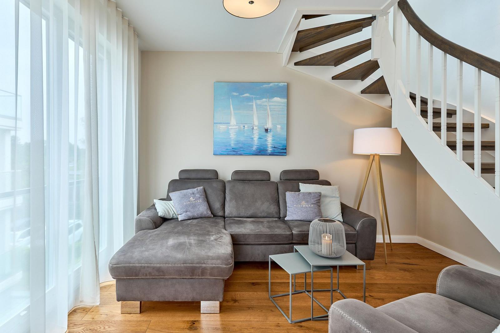 Wohnzimmer mit grauem Sofa, Stehlampe und Bild an der Wand