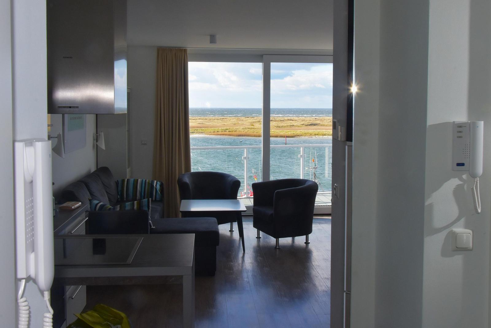 Wohnung mit Blick auf Wasser und Strand. Möbel und Küchenzeile sichtbar.