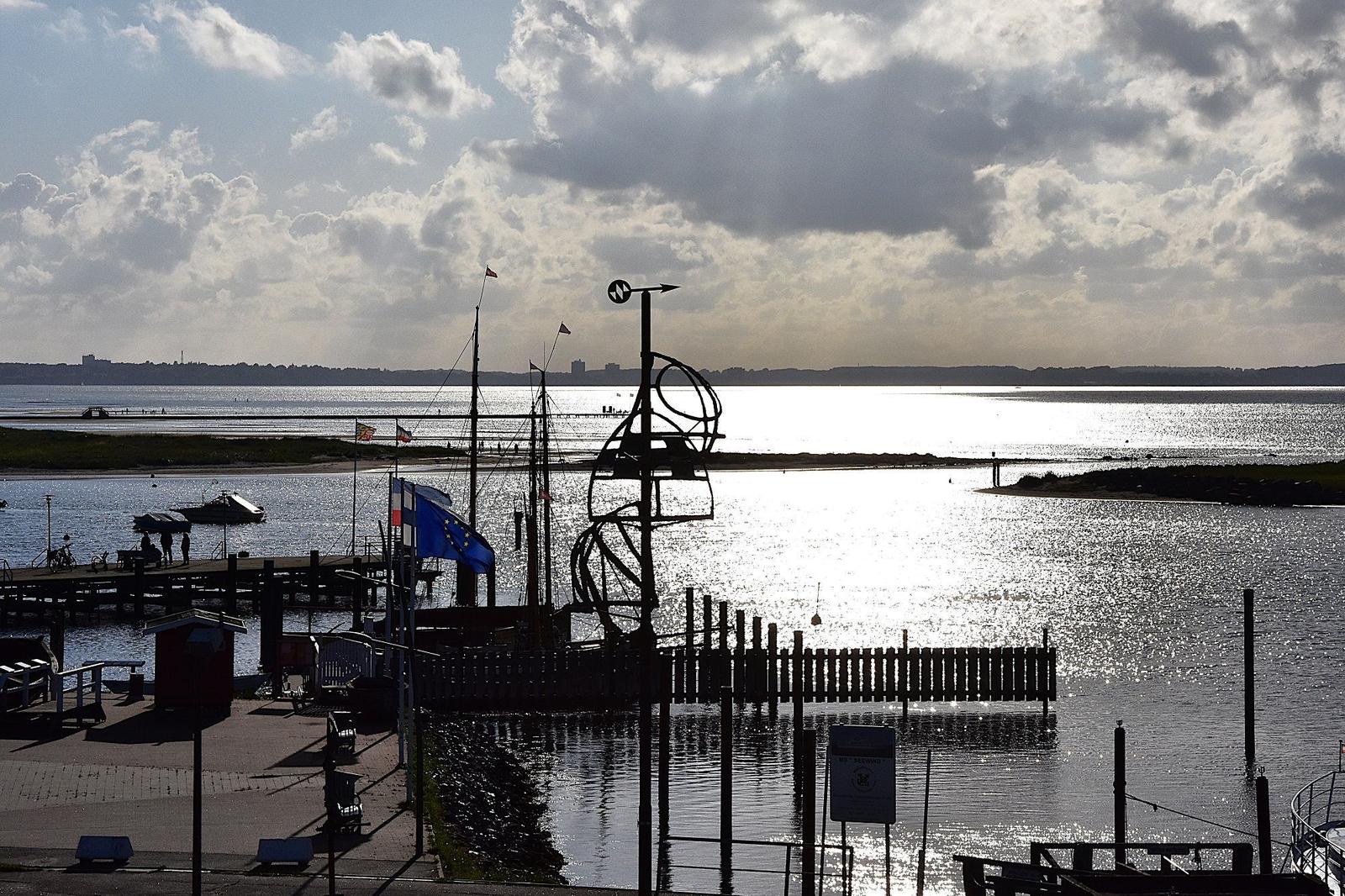 Hafen mit Steg, Flaggen und Blick auf Wasser und Horizont.