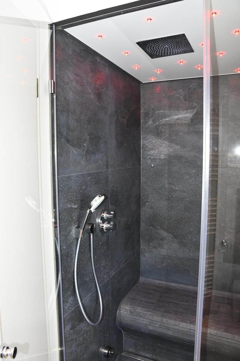 Dusche mit Duschbrause, Sitzbank und LED-Beleuchtung an der Decke