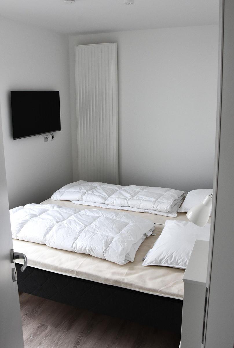 Schlafzimmer mit Doppelbett, Fernseher und Heizung.