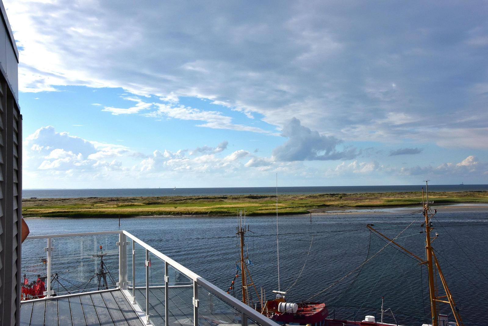 Terrasse mit Blick auf Hafen und Meer unter bewölktem Himmel.
