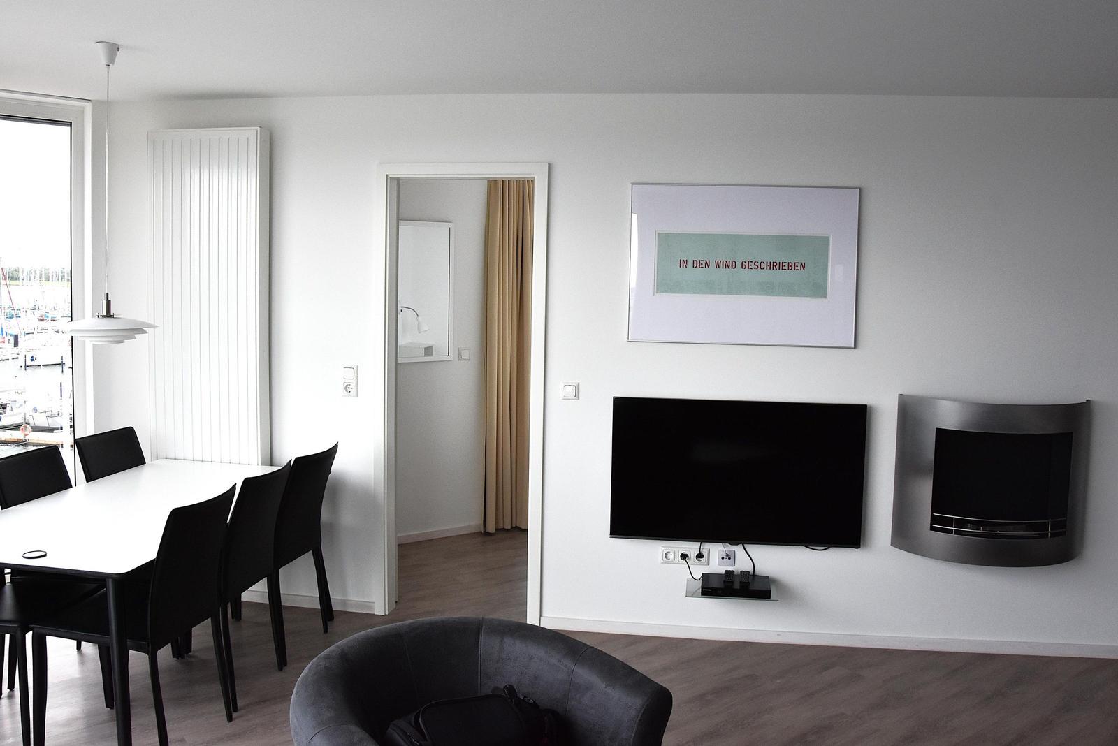 Wohn- und Essbereich mit TV, Kamin und Blick auf Hafen.