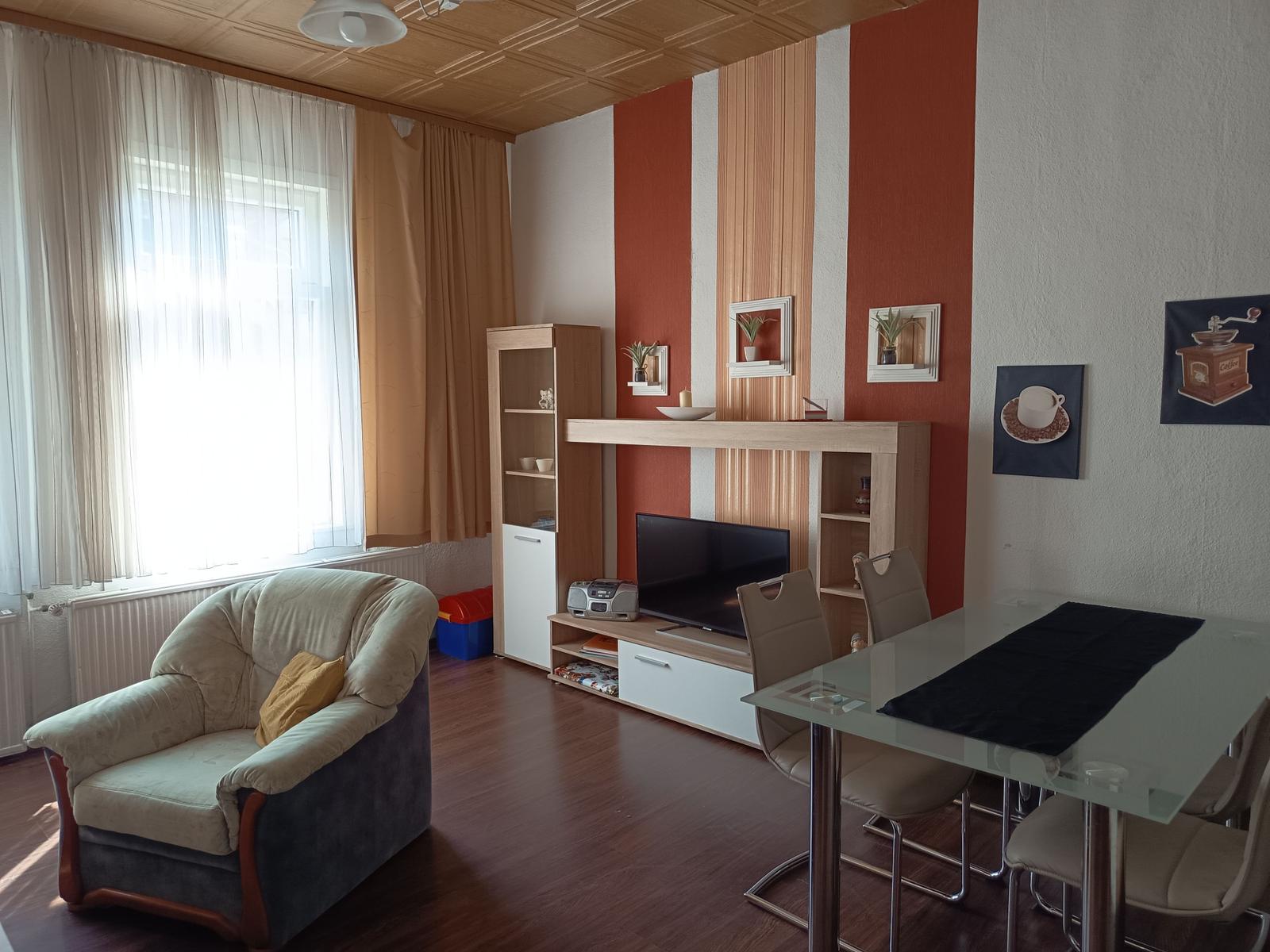 Wohnzimmer mit Essbereich, Fernseher und Sitzgelegenheit.