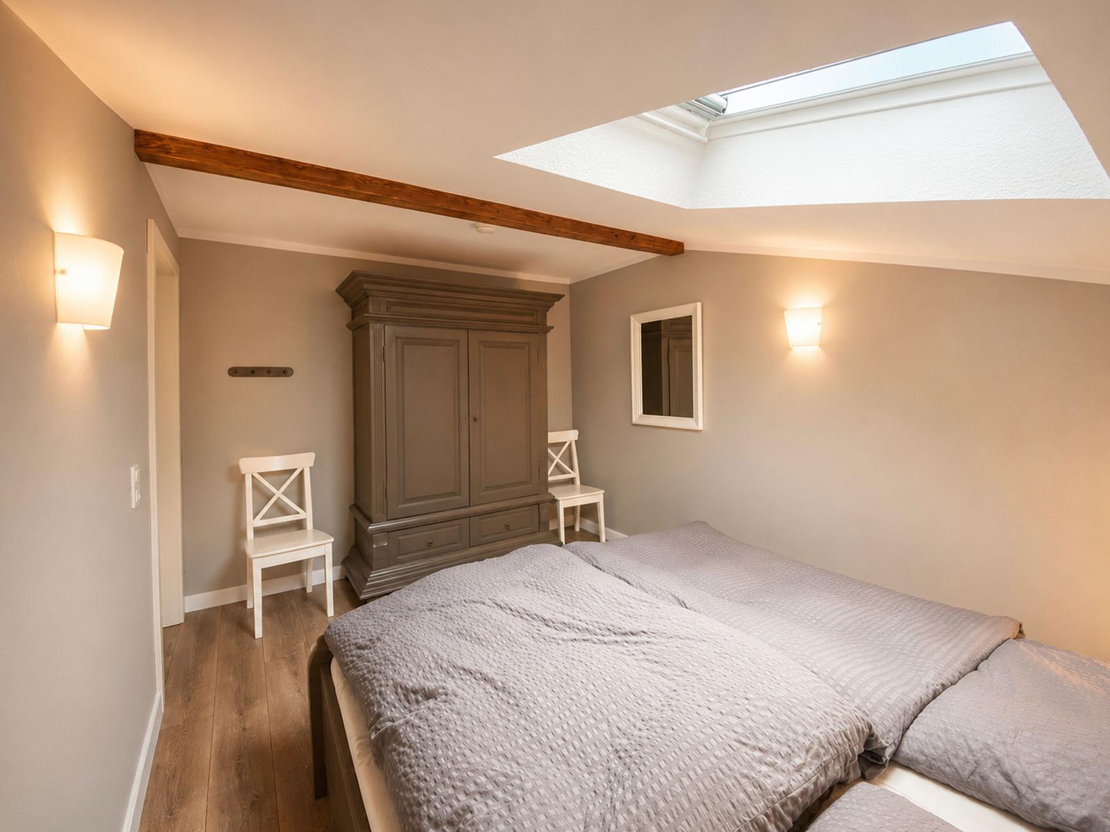 Schlafzimmer mit Doppelbett, Kleiderschrank und Dachfenster.