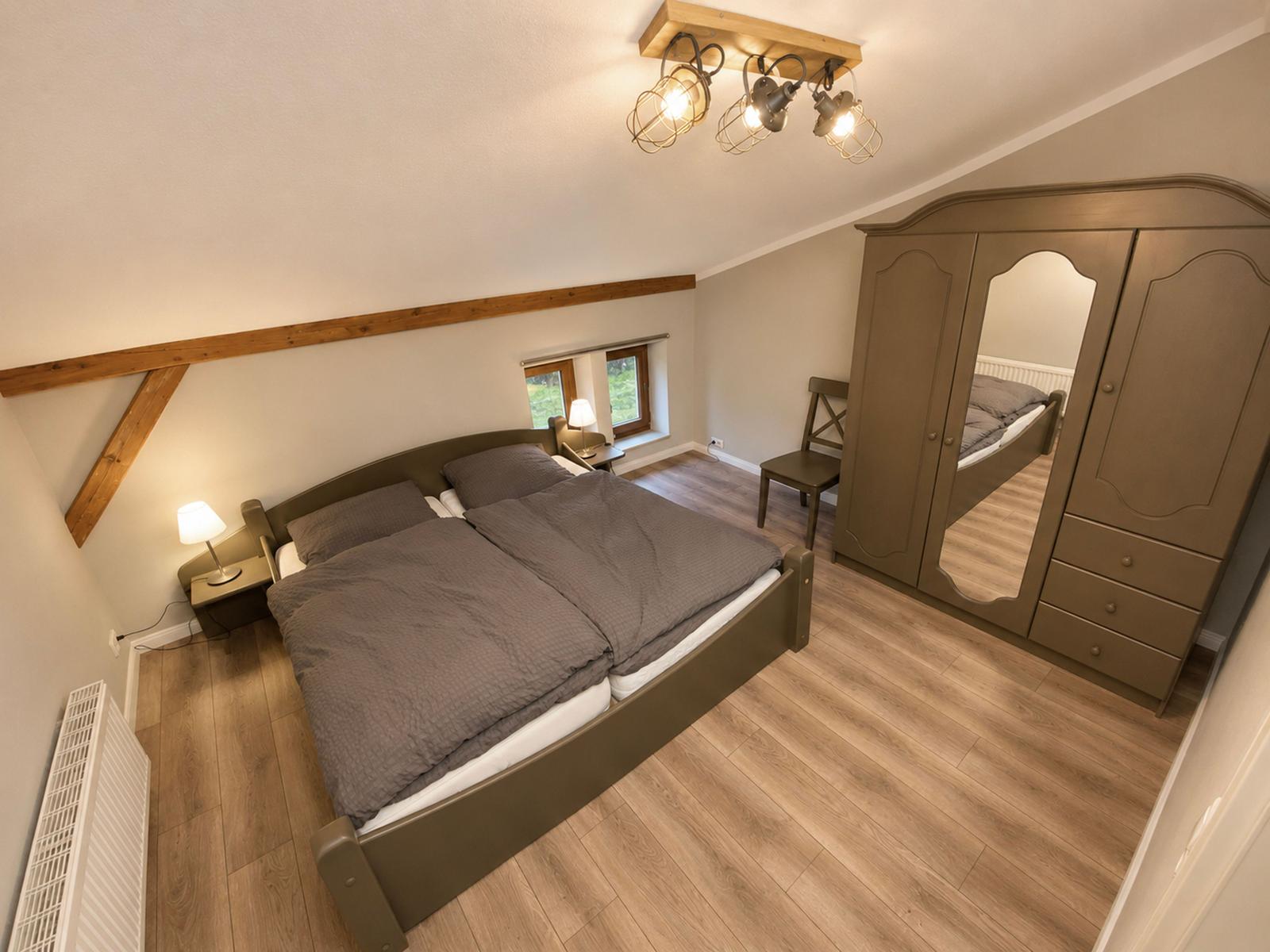 Schlafzimmer mit Doppelbett, Kleiderschrank und Holzboden.