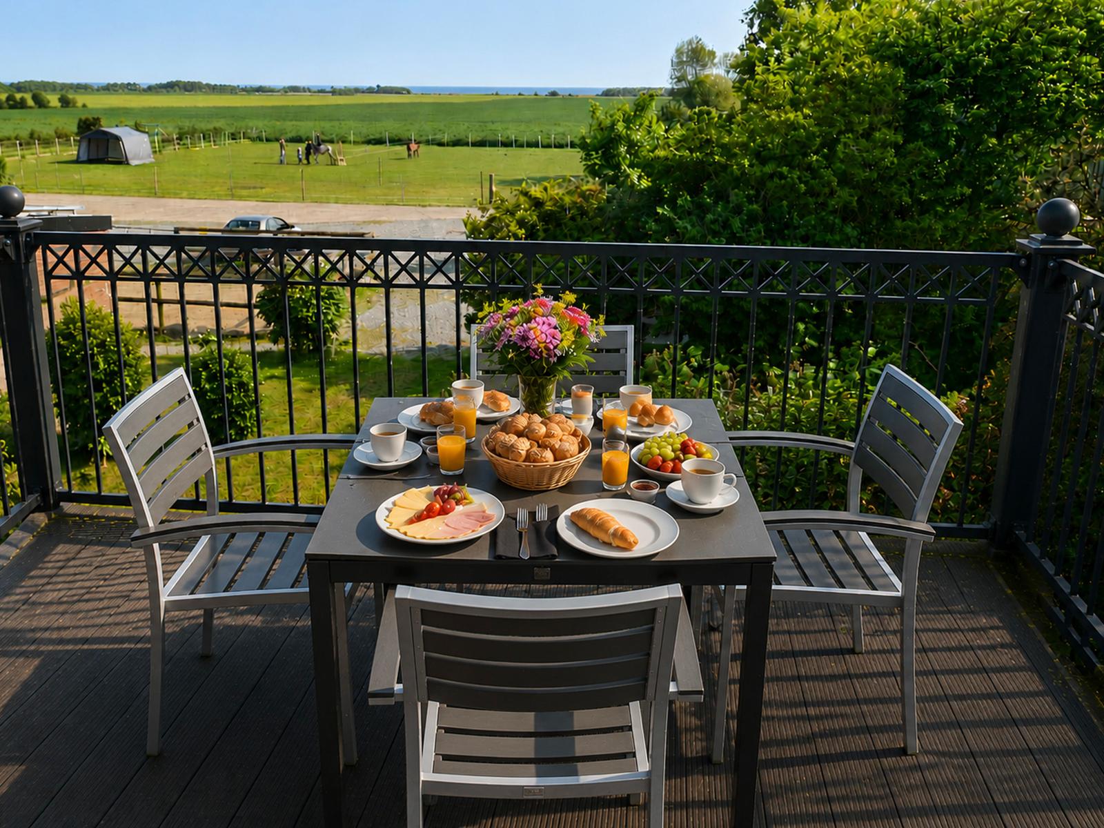 Frühstückstablett auf Terrasse mit Blick auf grünes Feld und Horizont.