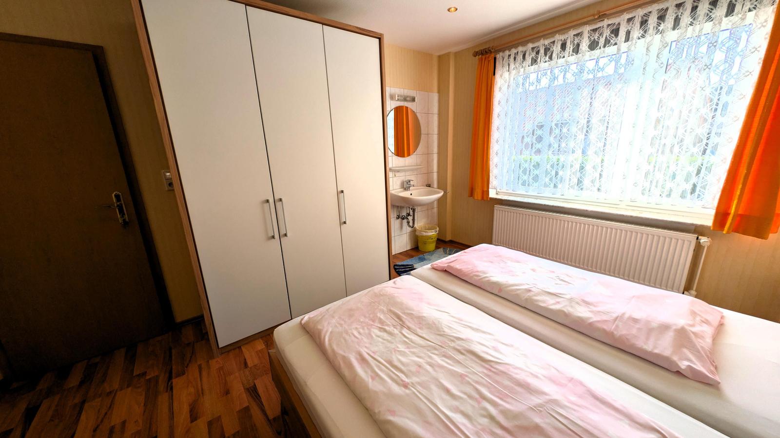 Schlafzimmer mit Doppelbett, Kleiderschrank und Waschbecken