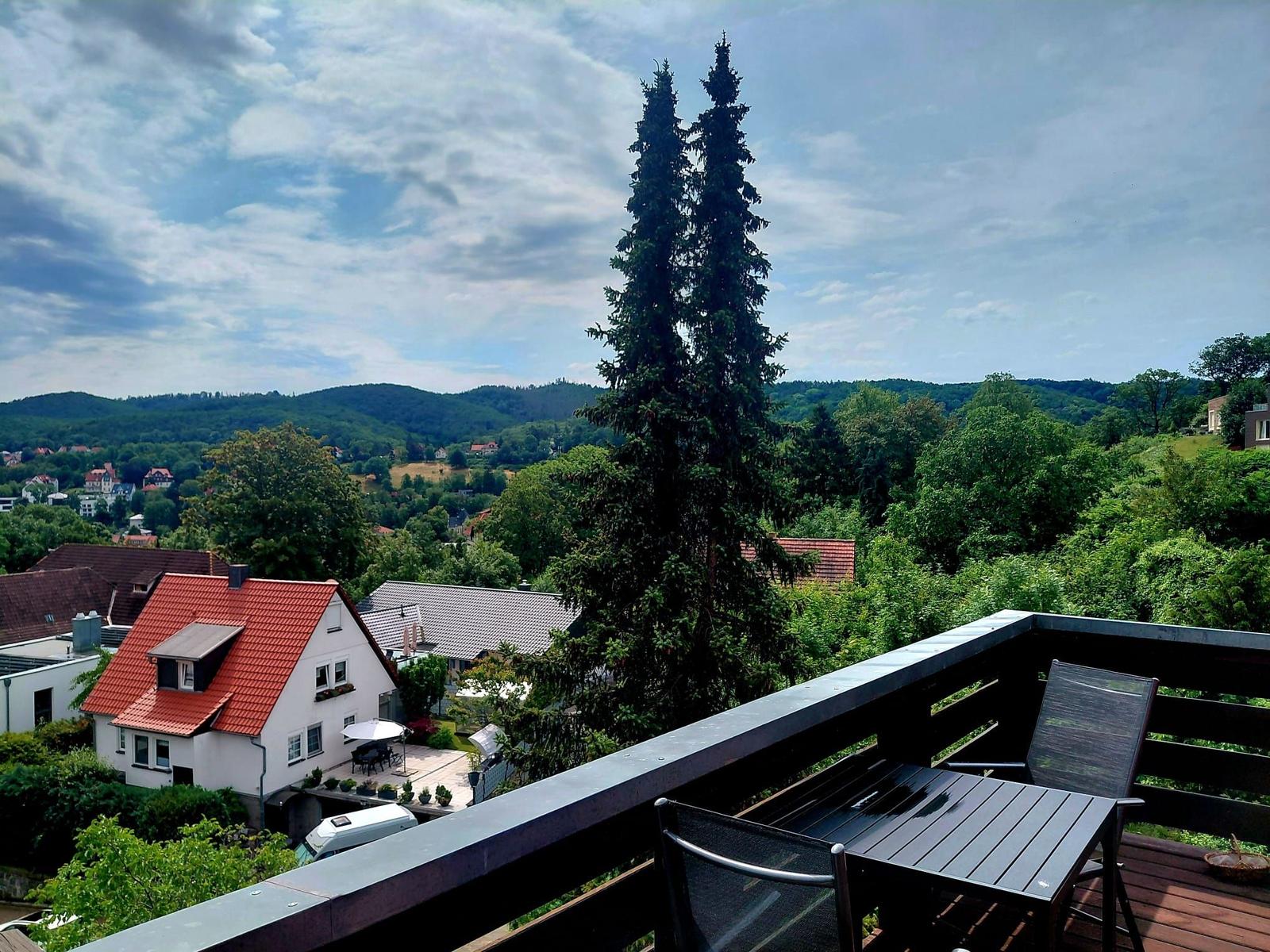 Terrasse mit Tisch und Stühlen bietet Blick auf grüne Landschaft und Häuser.