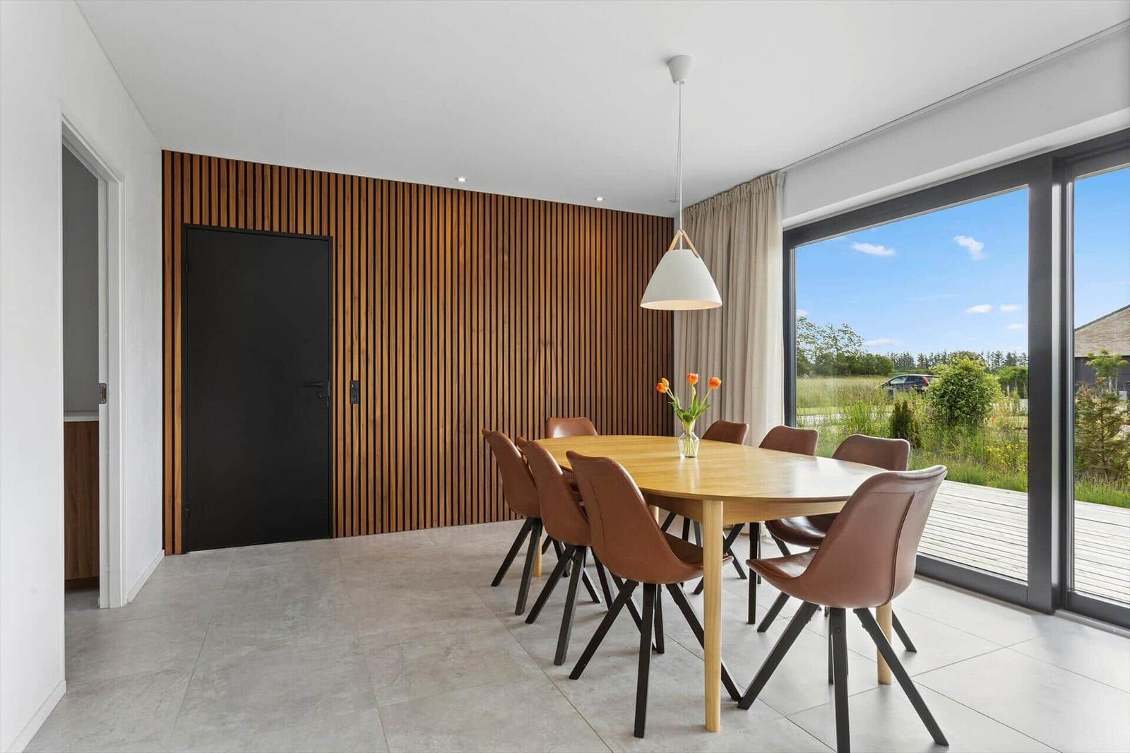 Esszimmer mit Holztisch, braunen Stühlen und großem Fenster zur Aussicht.