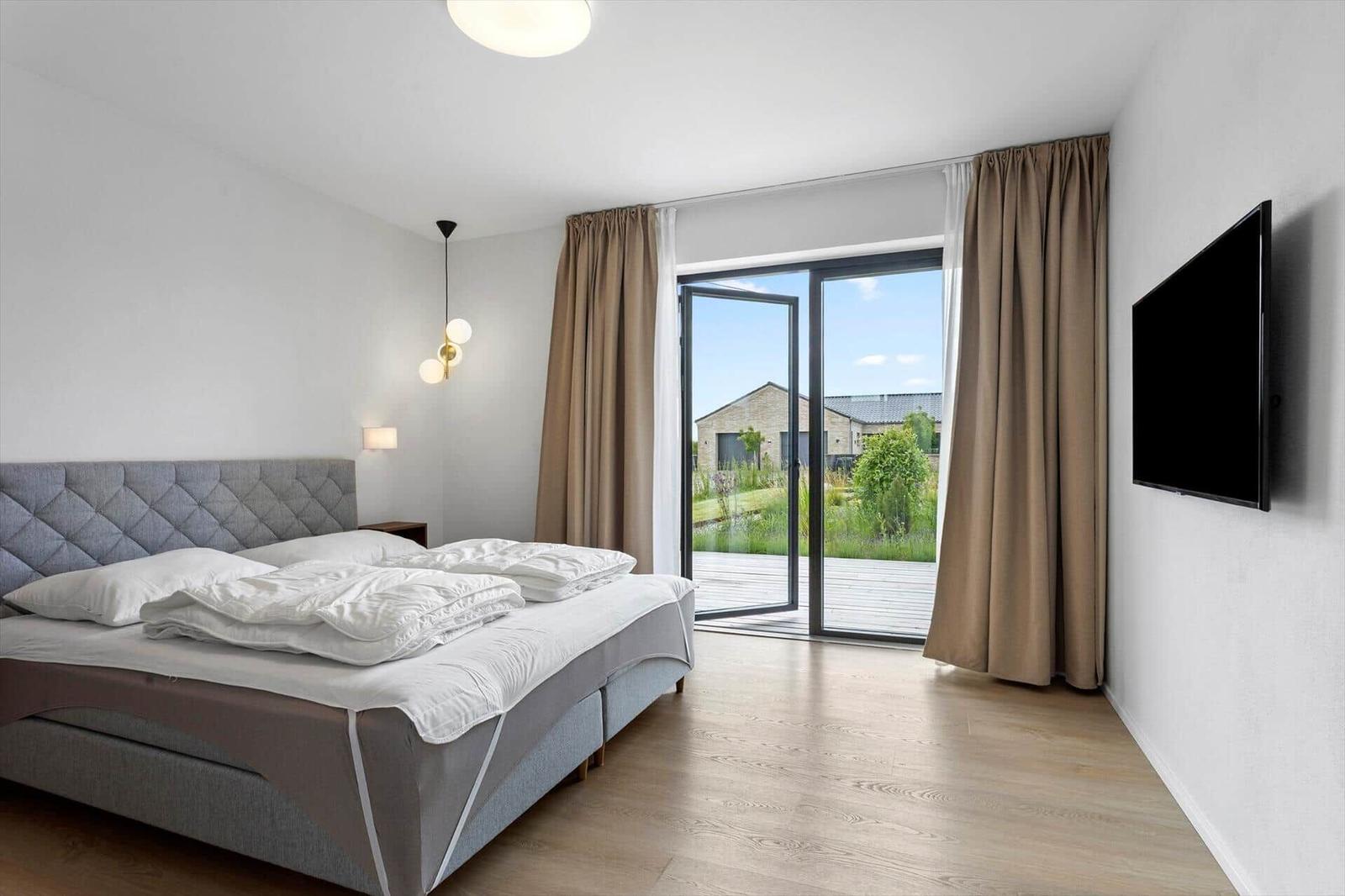 Schlafzimmer mit Bett, TV und Balkonblick.