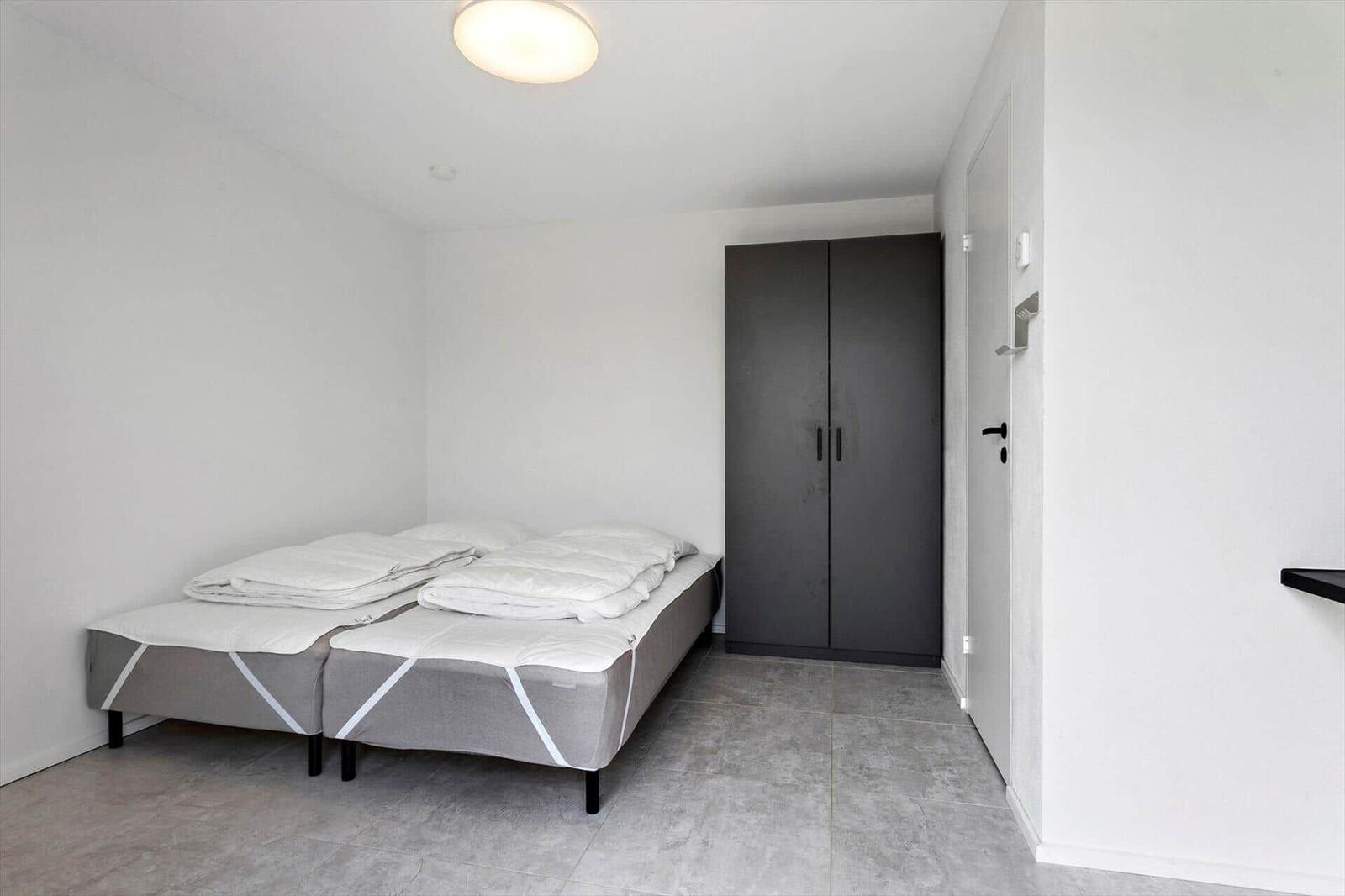 Schlafzimmer mit zwei Matratzen, Kleiderschrank und Bodenfliesen.