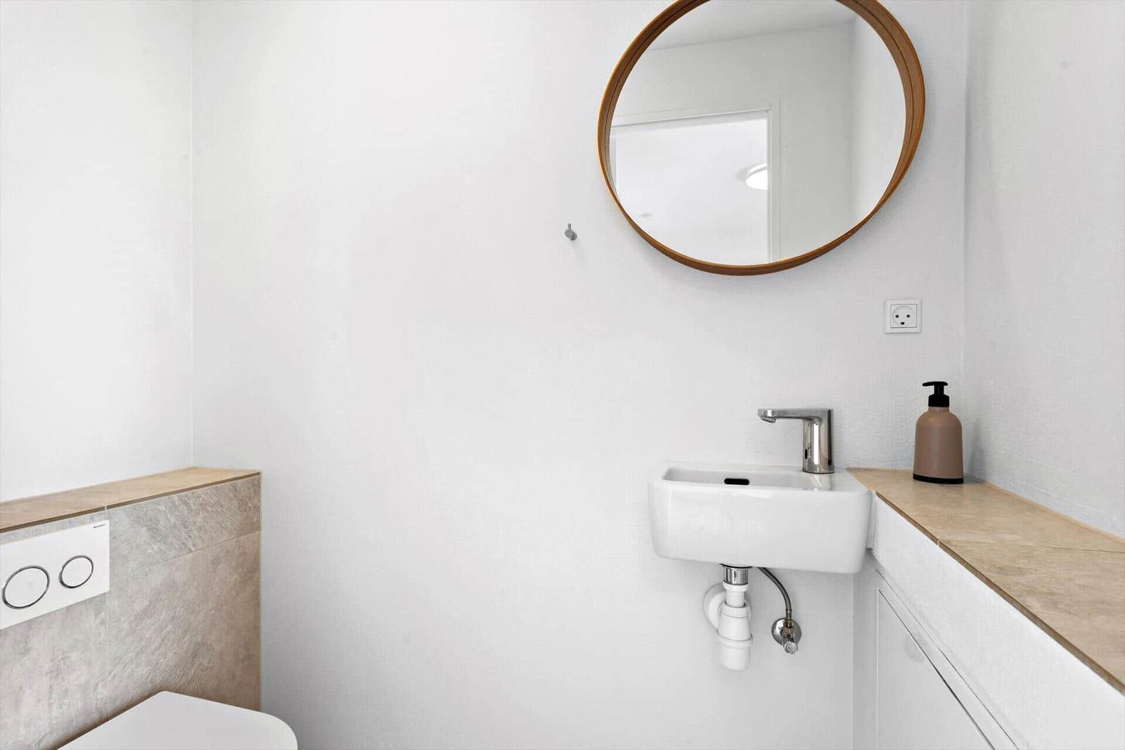 Bad mit Waschbecken, Spiegel und Toilette.
